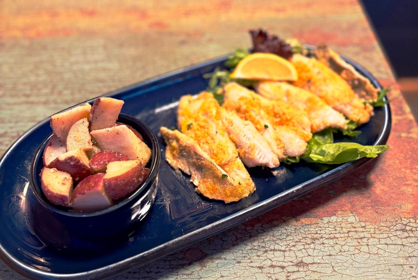 Fish fillets with seasoned red potatoes on a blue platter.