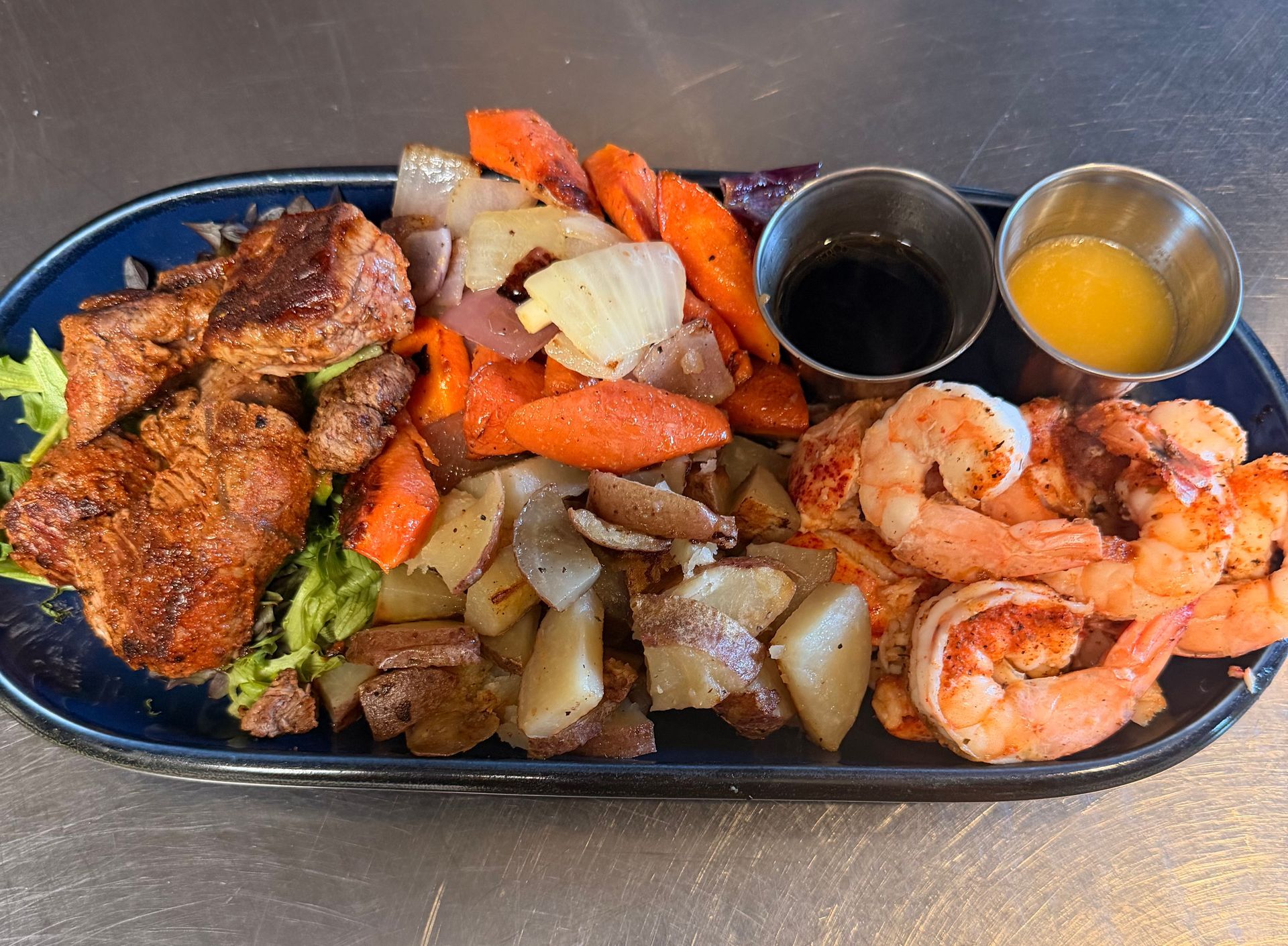 Grilled chicken, shrimp, and roasted vegetables on a plate, with two dipping sauces.