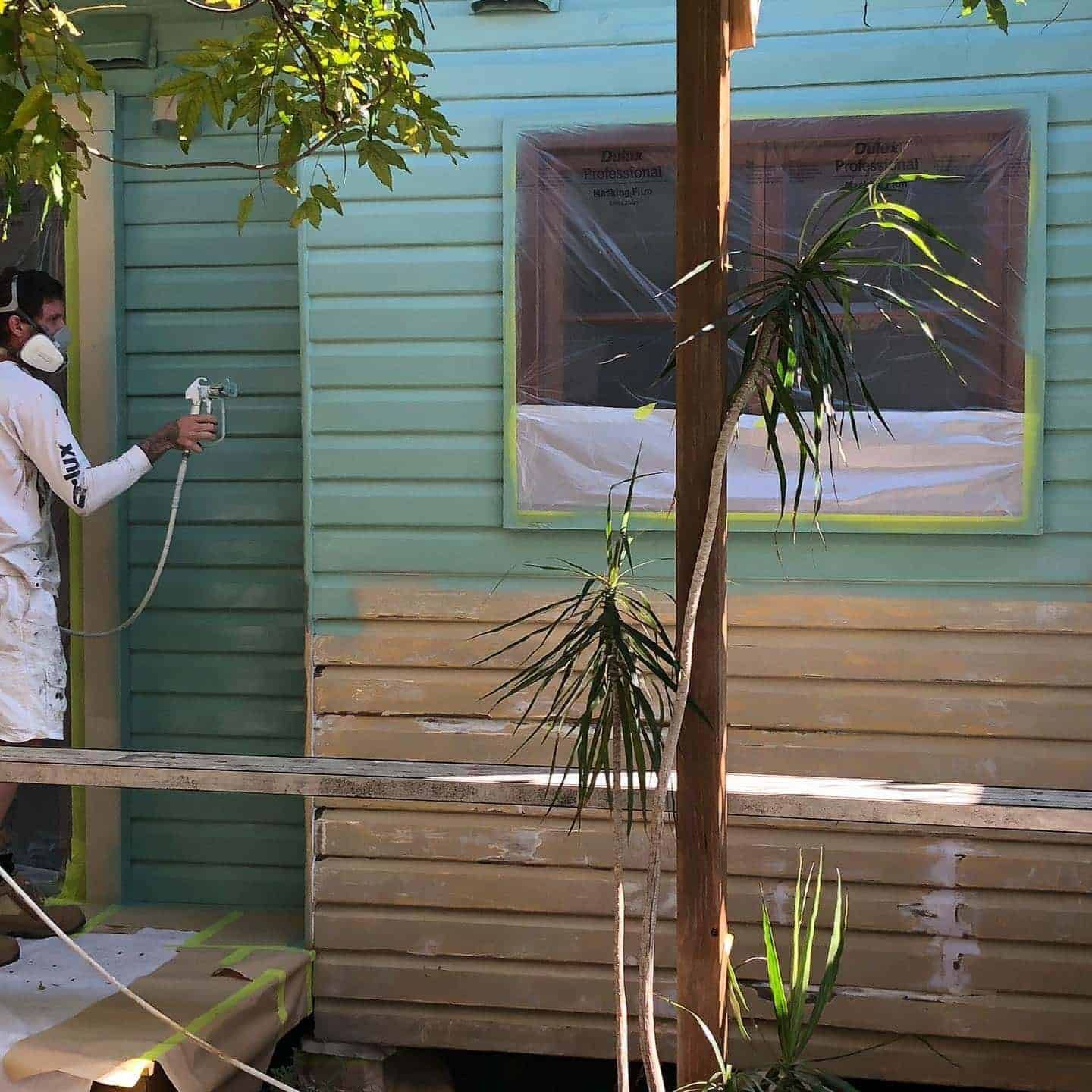 A Man Wearing a Mask is Spray Painting a House — The Big Bearded Painter In Stroud, NSW