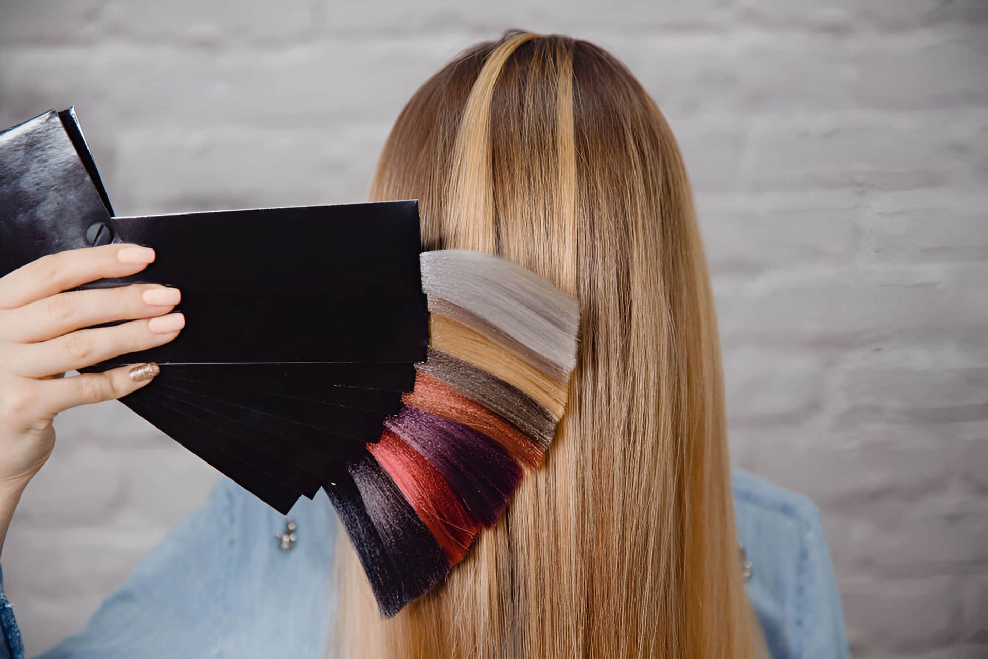 A Woman Is Holding A Palette Of Hair Colors In Front Of Her Hair — Kabello Salon In Airlie Beach, QLD