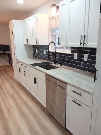 Modern white kitchen with black accents: cabinets, backsplash, and hardware. Stainless steel appliances.