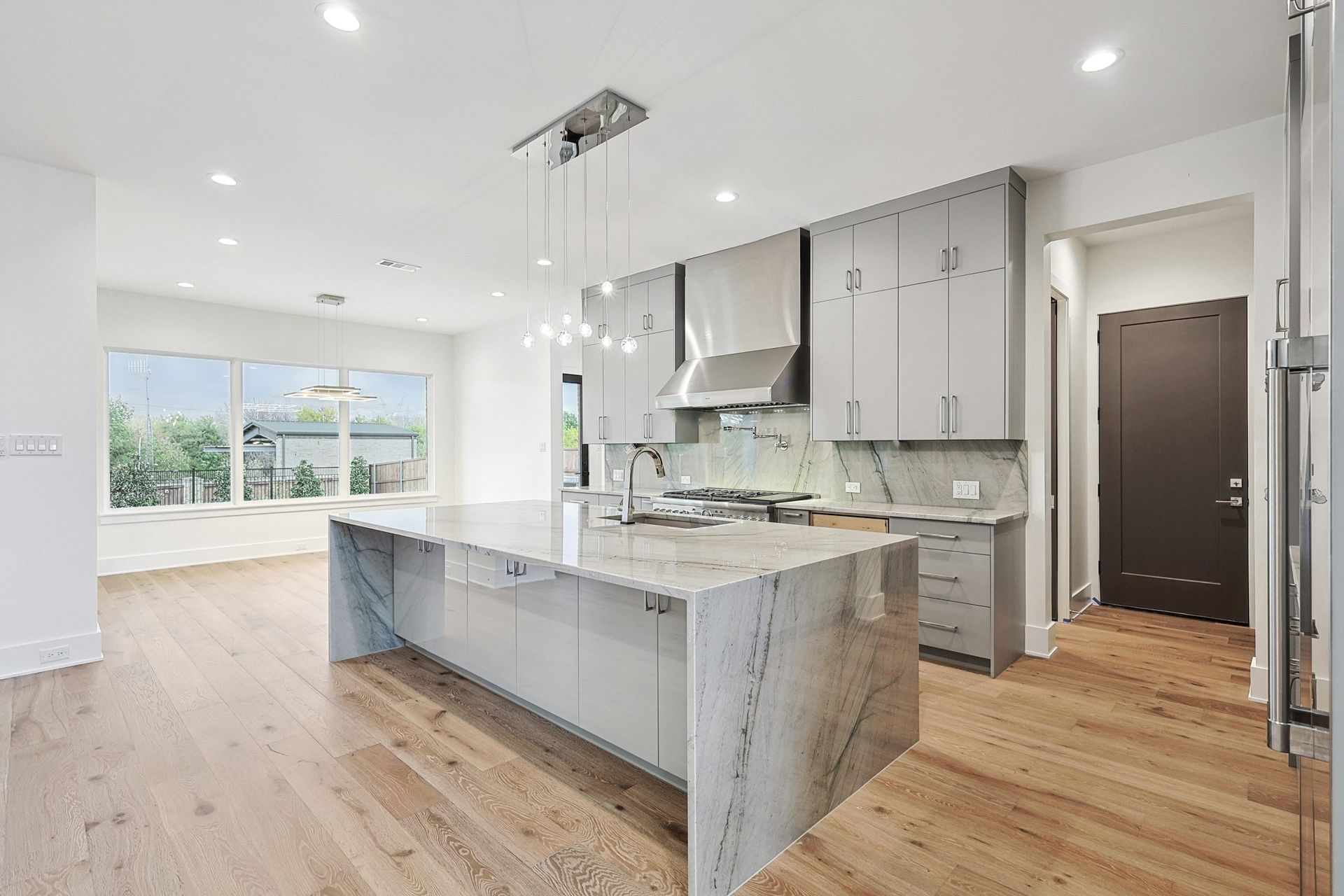 Modern kitchen with large island, light gray cabinets, and hardwood floors.