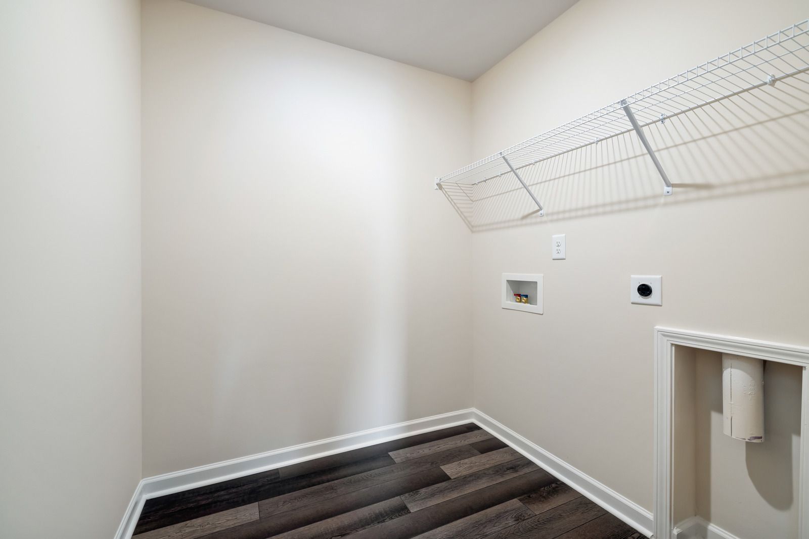 Man in overalls painting a green wall with a roller, next to a ladder and bucket in a room.