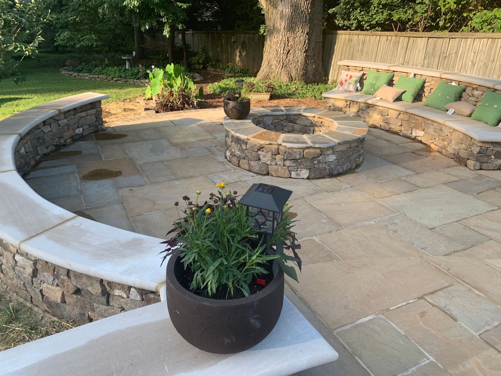 Stone patio with a view, surrounded by trees. Overlooks a valley under a cloudy sky.