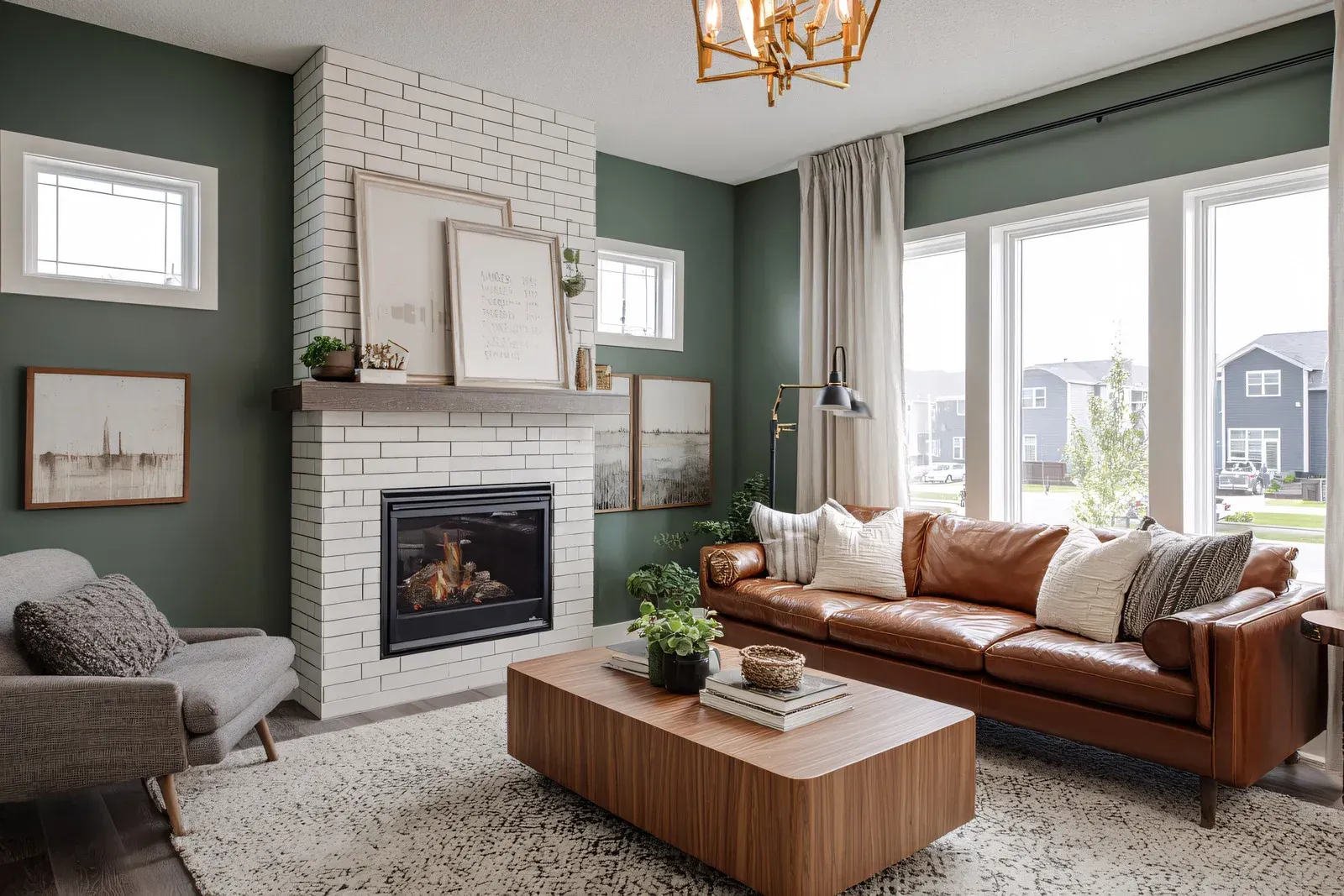 Green living room with brick fireplace, brown leather sofa, wooden coffee table, and large windows.