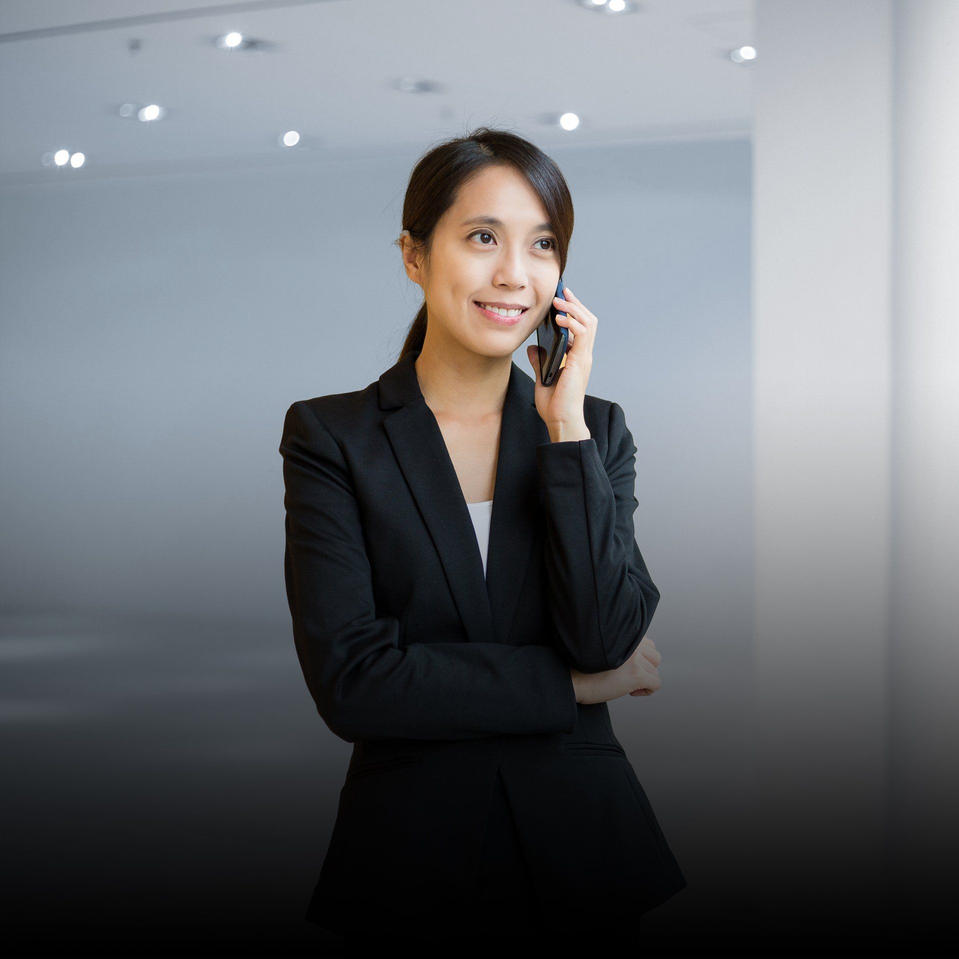 A woman in a black suit is talking on a cell phone