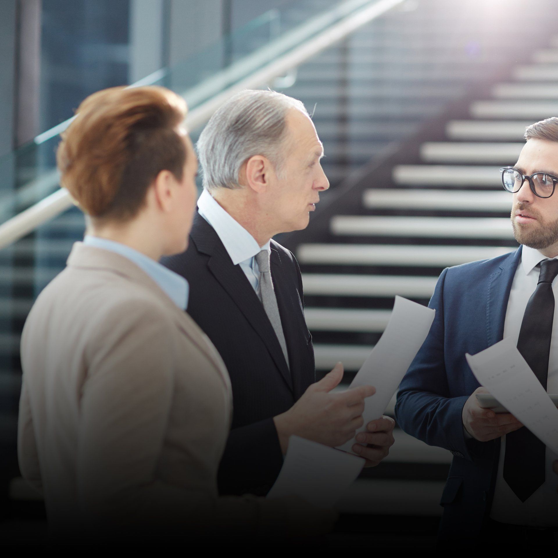 A man in a suit and tie is talking to two other men