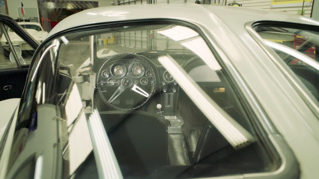 Interior view of a classic silver sports car with a black steering wheel and dashboard.