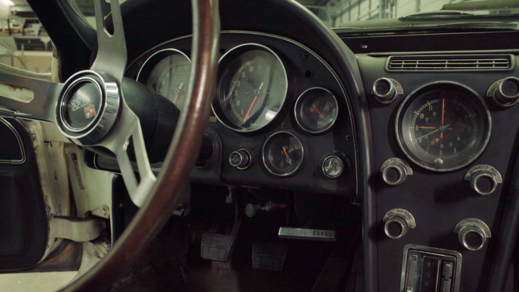 Classic car dashboard: gauges, steering wheel, dark interior.
