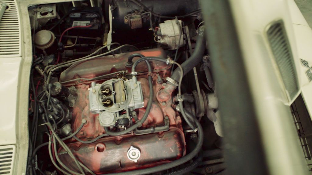 White classic car engine, red engine block, carburetor, wires, and other components visible.