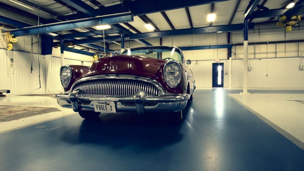 Classic maroon convertible in a well-lit garage.