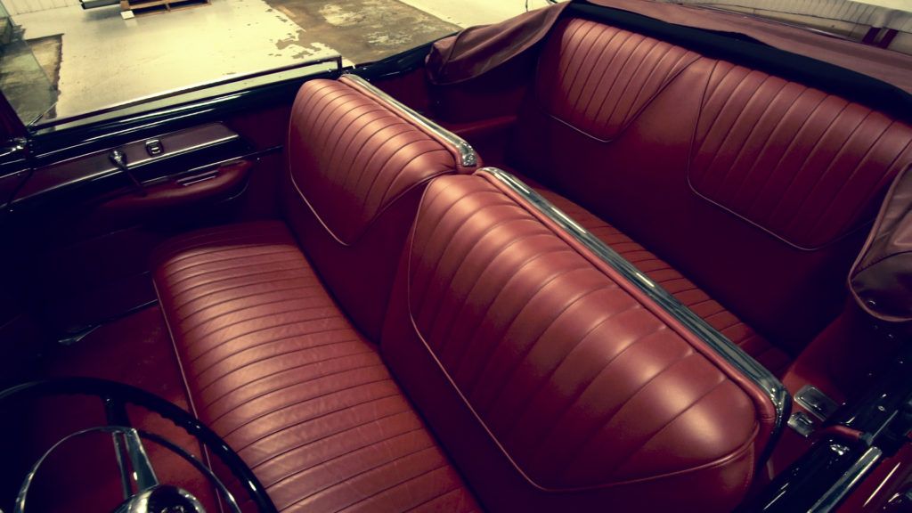 Red leather interior of a vintage convertible car, including seats, steering wheel, and dashboard.