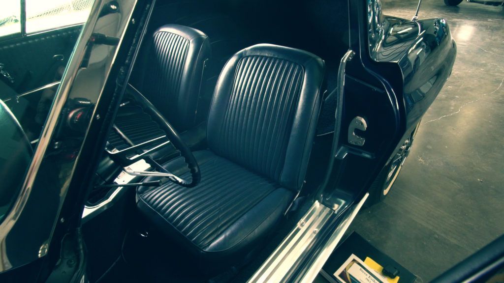 Black classic car interior with blue seats and steering wheel.