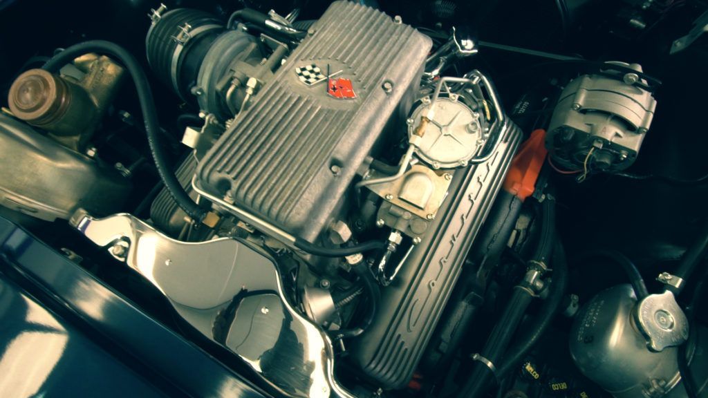 Silver engine of a classic car with red and black accents.