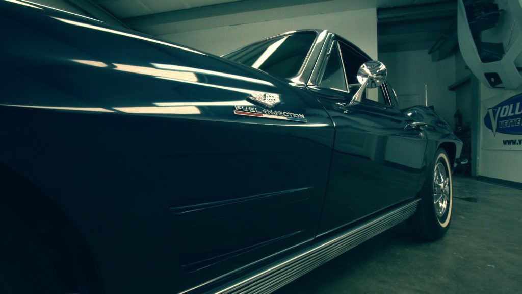 Dark blue classic convertible car parked in a garage with chrome detailing.