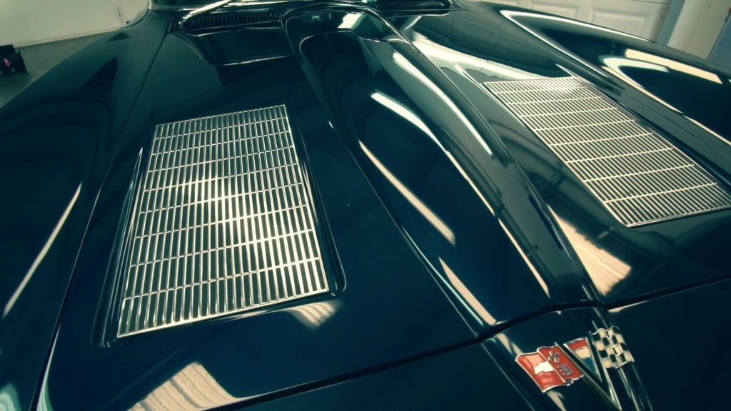 Dark blue classic car hood with chrome vents and checkered flag emblem.