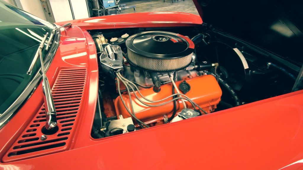 Bright red classic car engine bay with orange engine block.