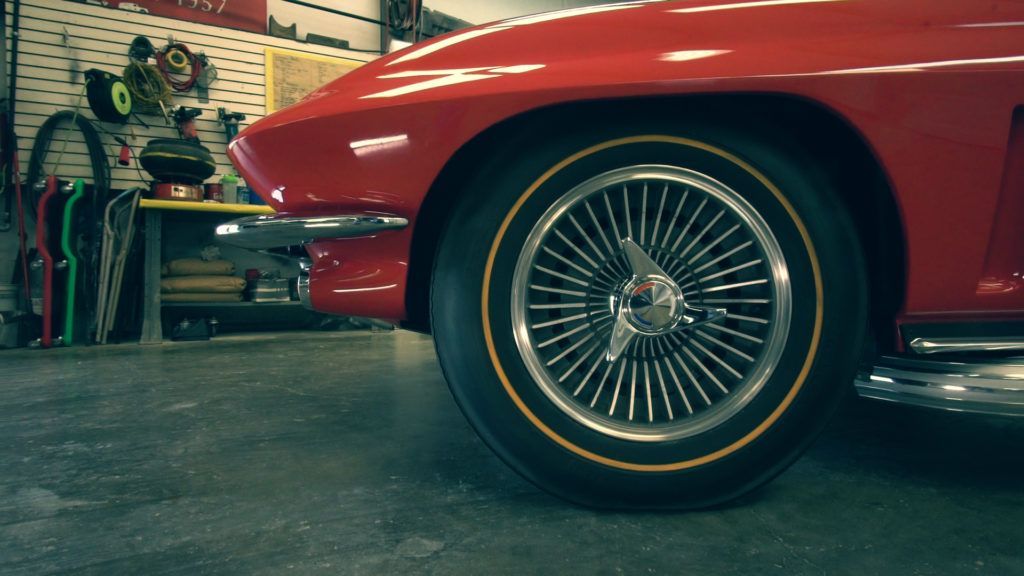 Red classic car, spoked wheels, parked in a garage.