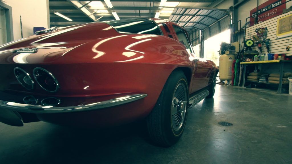 Red classic Corvette in a garage with chrome accents.