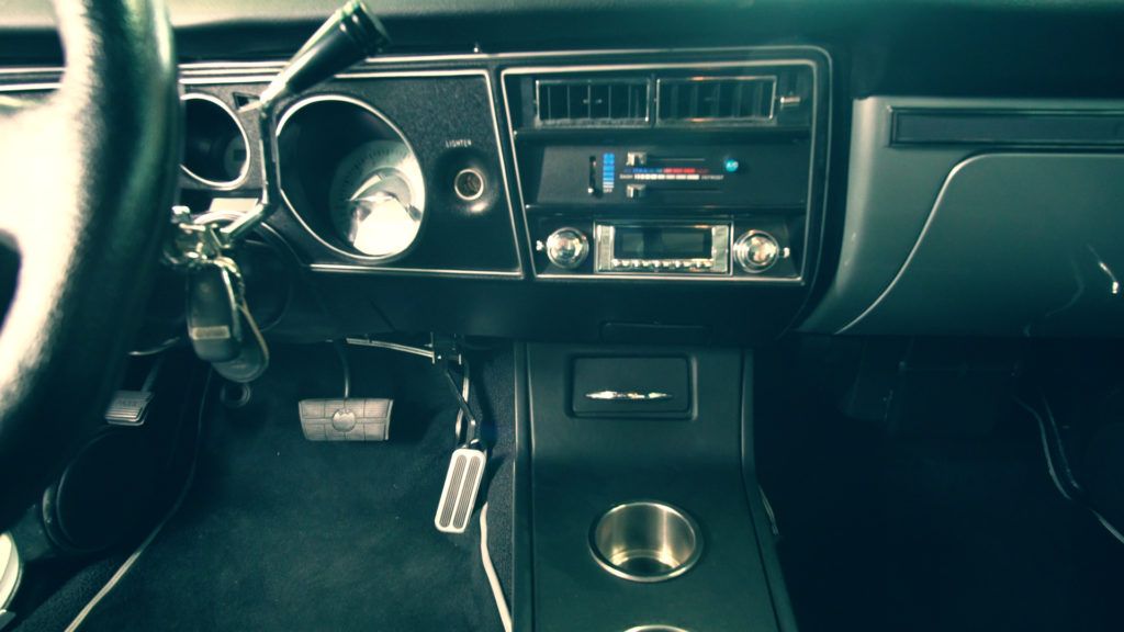 Black and gray car interior. Dashboard with gauges, radio, and console with cup holders.