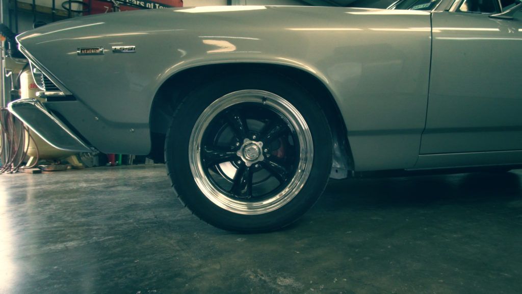 Silver classic car with black rims in a garage.