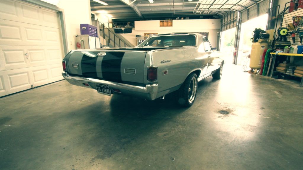 Silver El Camino with black stripes, in a garage.