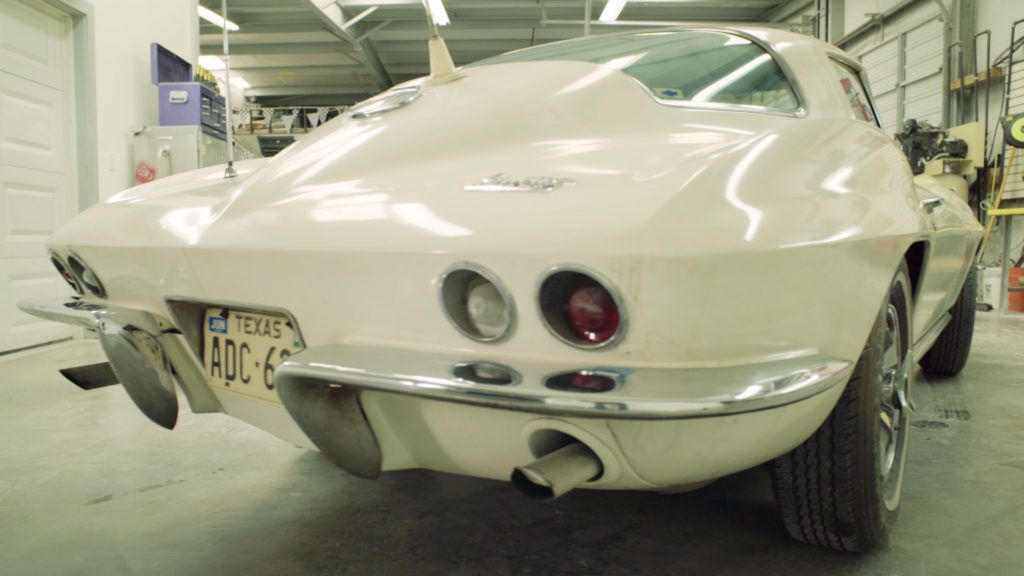 White classic Corvette, rear view, in a garage; Texas license plate.