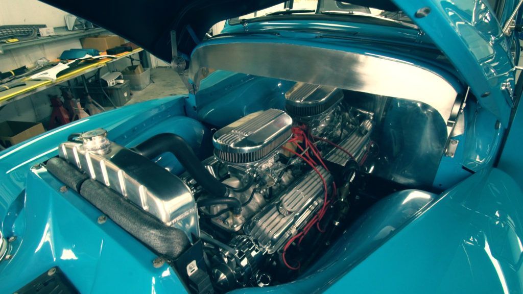 Blue classic car engine bay with a chrome engine.