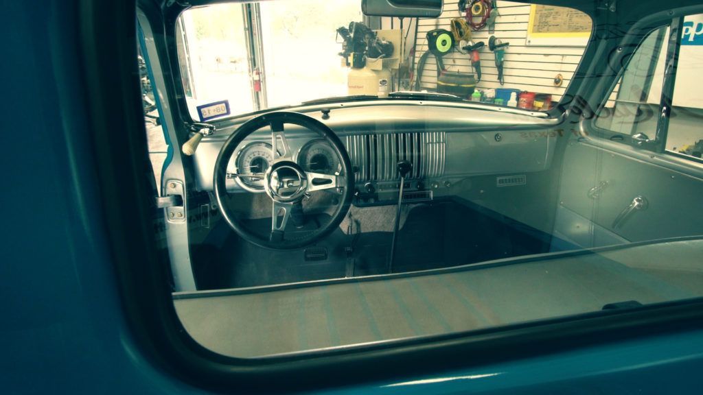 Interior view of a classic blue pickup truck, showcasing the dashboard, steering wheel, and gauges.