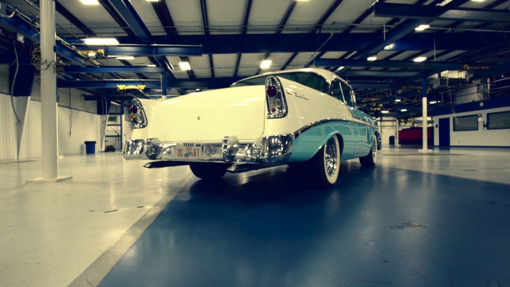 Vintage two-tone car, white and blue, parked inside a large warehouse.