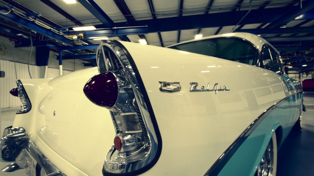 White and turquoise classic car in a garage. Chrome detailing, rear tail fins, and 