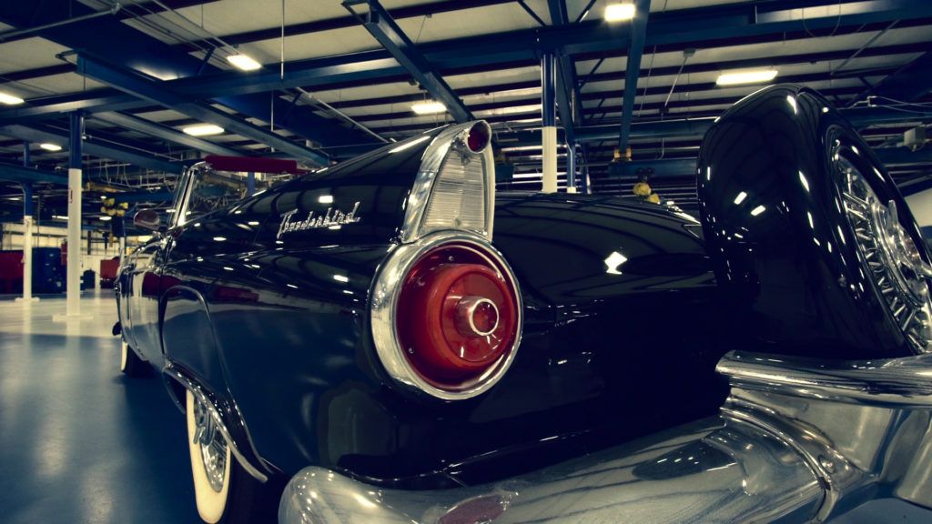 Black classic car rear, in a showroom; chrome details, red taillight.