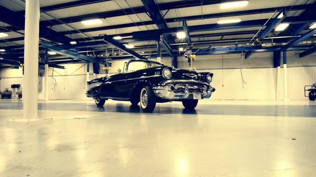 Black classic convertible in a spacious, well-lit garage.