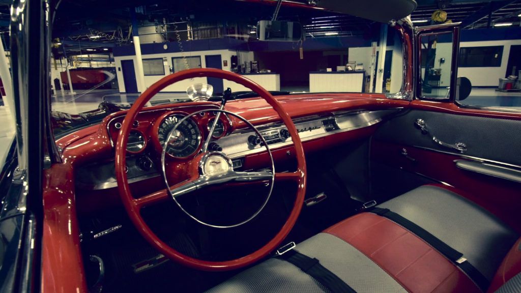 Red vintage car interior: steering wheel, dashboard, seats.
