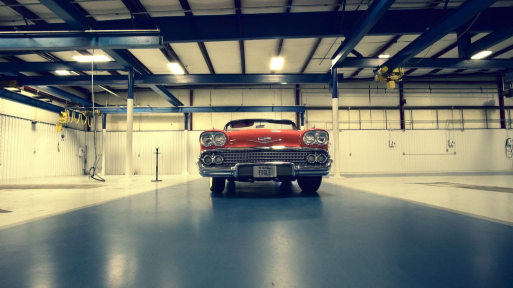 Red classic car in a car wash bay.