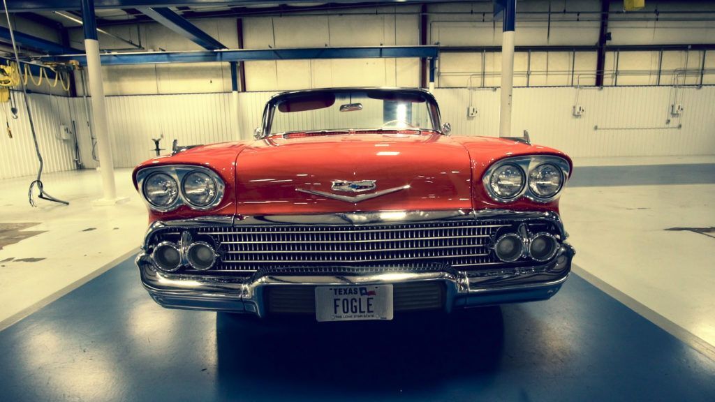 Red vintage convertible car in a garage, chrome details, license plate 
