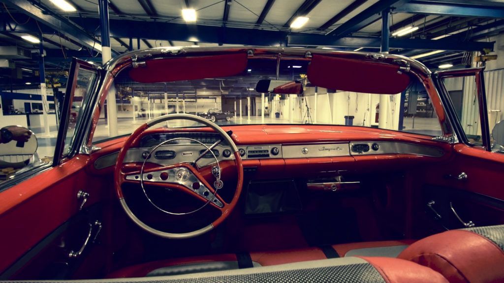 Red vintage convertible car interior, detailed dashboard, open roof.
