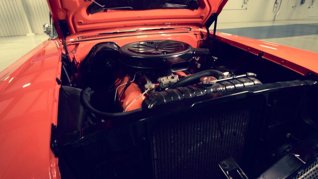 Bright orange classic car engine bay, showing engine and radiator.