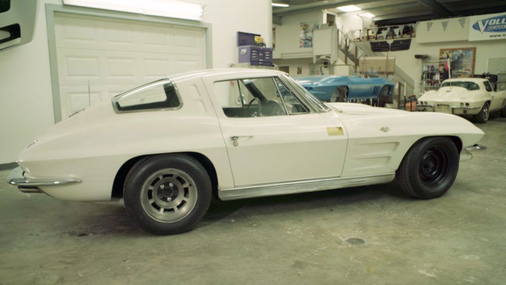 White 1960s Corvette coupe in a garage, with black wheels and a slightly lowered stance.