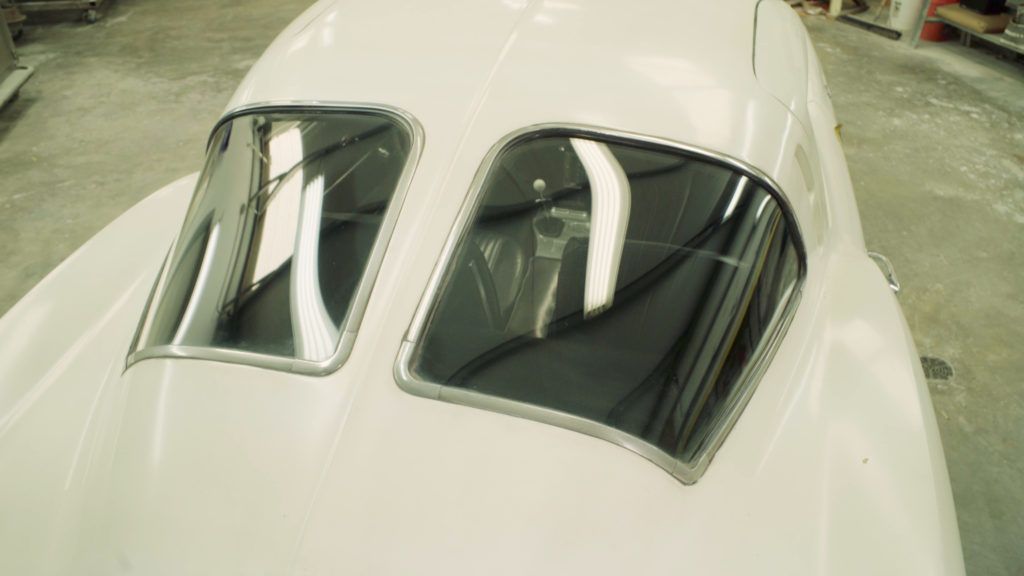 Two teardrop-shaped windows on a white vehicle's hood, with chrome trim.