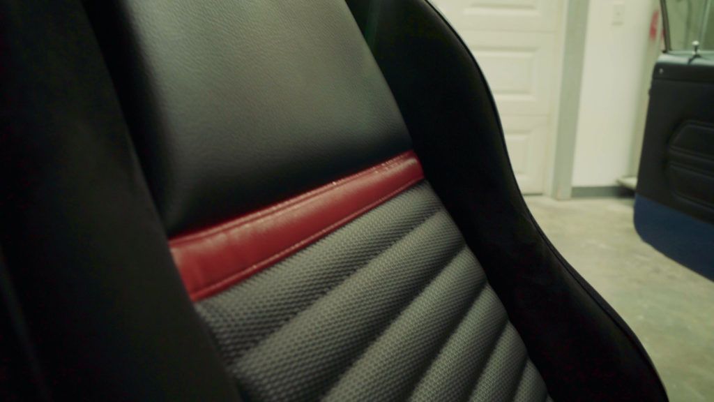 Black and red car seat with quilted pattern, in a garage.
