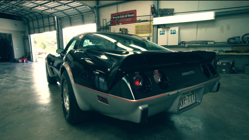 Black and silver Corvette sports car in a garage with a spoiler.