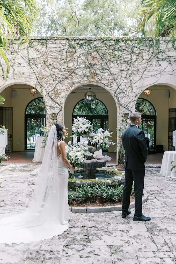 Bride in white dress faces groom in black suit.