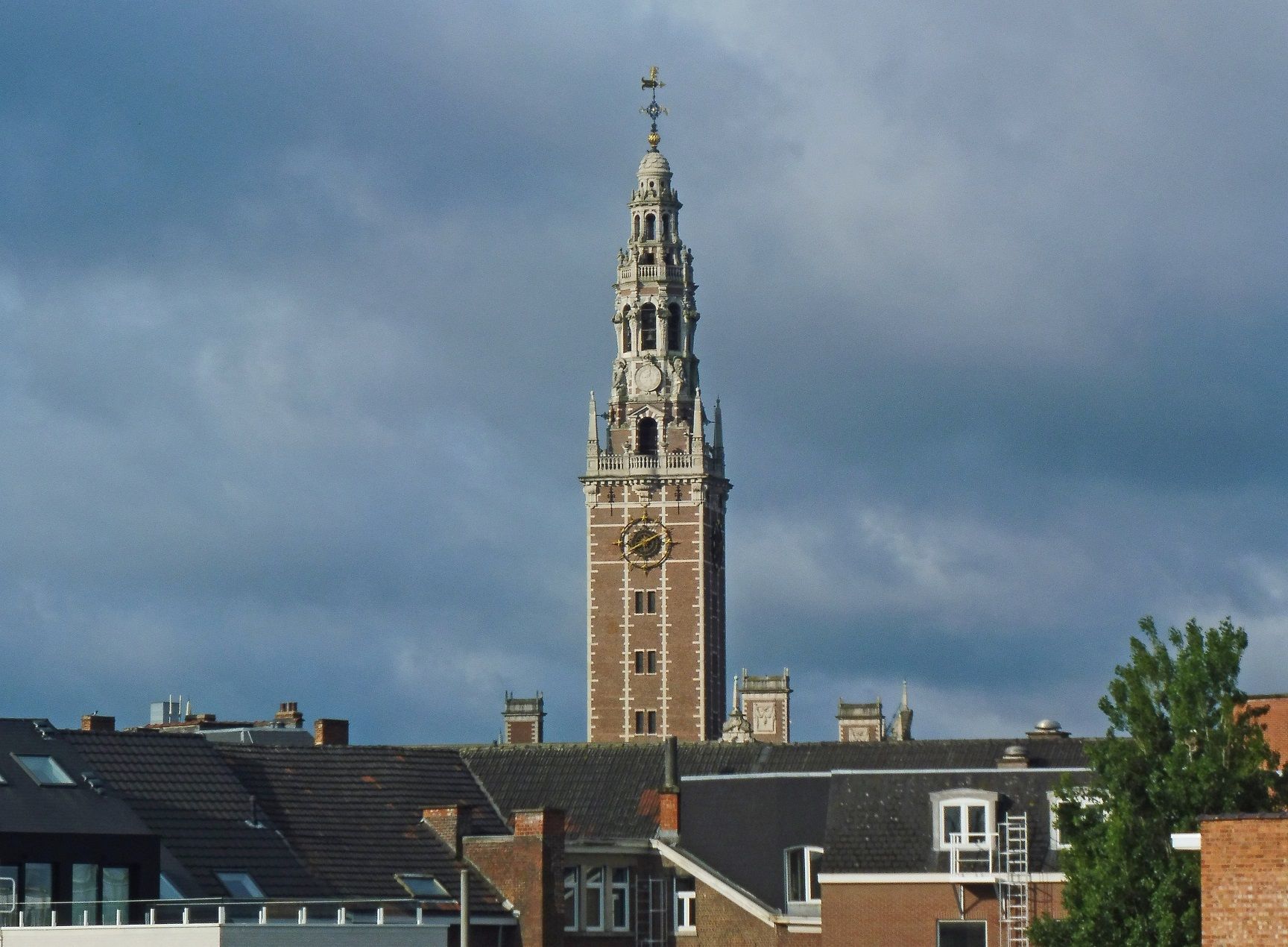 A clock tower with a cross on top of it