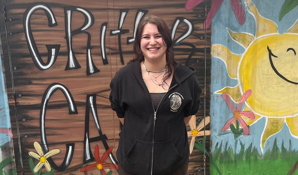 A woman standing in front of a Critter Care mural