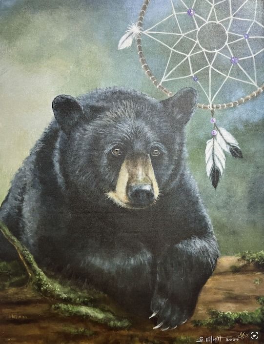 A black bear is sitting next to a dream catcher.