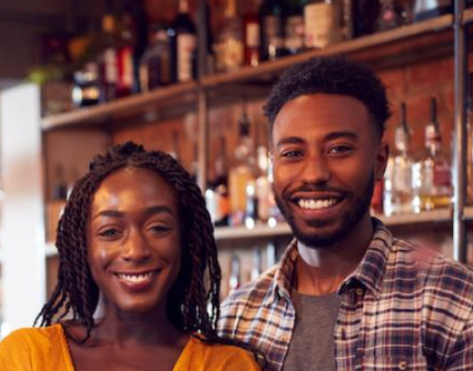 a man and a woman are posing for a picture in a bar .