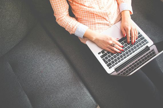 A woman is sitting on a couch using a laptop computer.