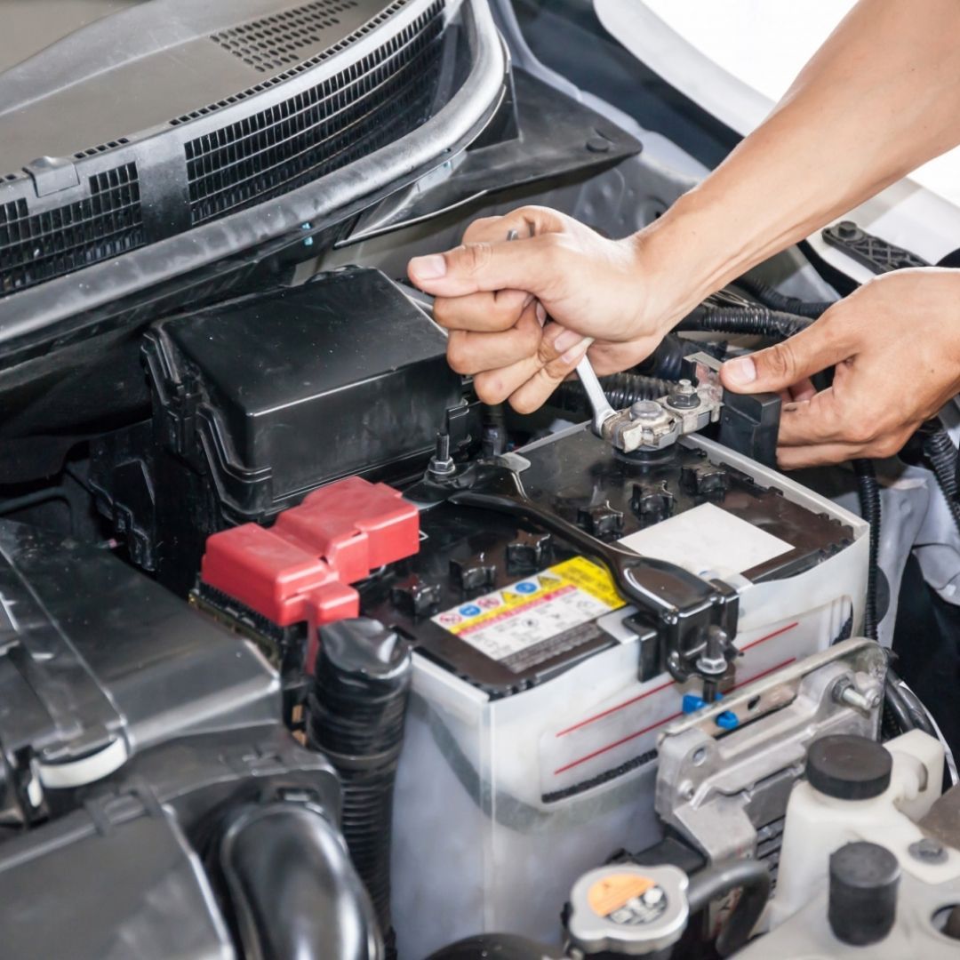 A person is working on a car battery with a wrench