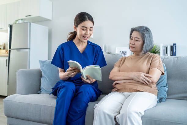 In home caregiver reading a book with an older adult during supportive care visit